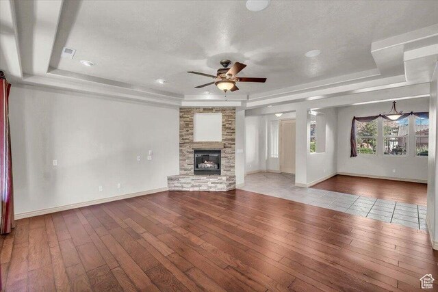 1319 W Red Butte Dr W, Washington, UT 84780 - unfurnished living room featuring hardwood / wood-style floors, ceiling fan, a raised ceiling, and a stone fireplace