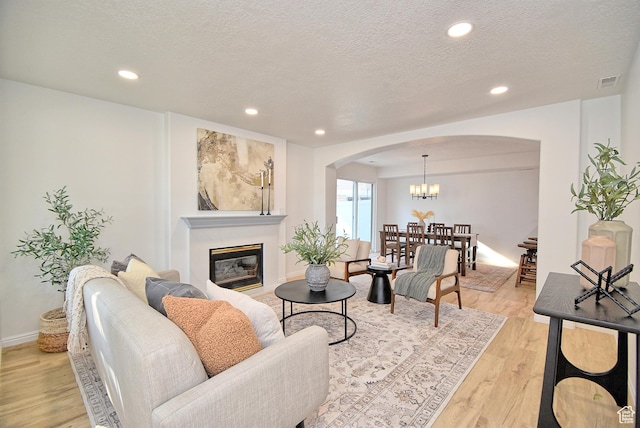 1323 S 1260 W, Orem, UT 84058 - living area featuring arched walkways, light wood finished floors, a glass covered fireplace, a chandelier, and recessed lighting