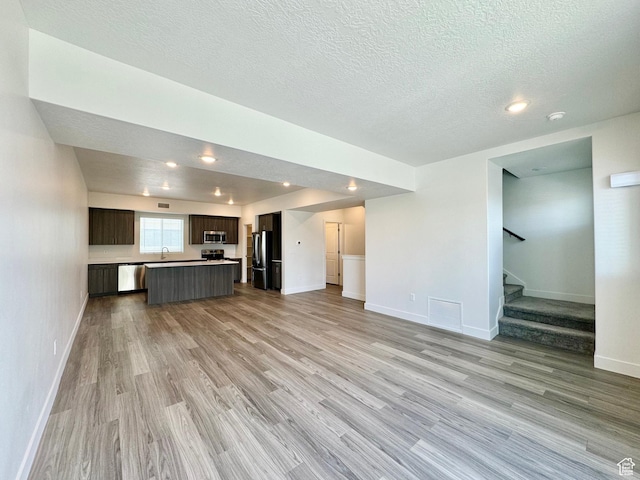2345 W Miles Unit D15, West Haven, UT 84401 - unfurnished living room with light wood-style floors, a textured ceiling, stairway, and recessed lighting