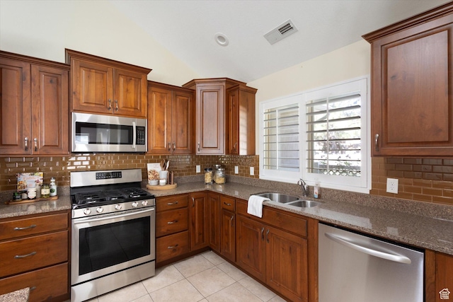 1867 W 9270 S Unit C, West Jordan, UT 84088 - kitchen with appliances with stainless steel finishes, vaulted ceiling, light tile patterned floors, tasteful backsplash, and brown cabinets