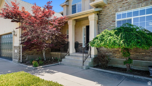 11597 N Sunset Hills Dr, Highland, UT 84003 - doorway to property featuring stone siding, a garage, stucco siding, and covered porch