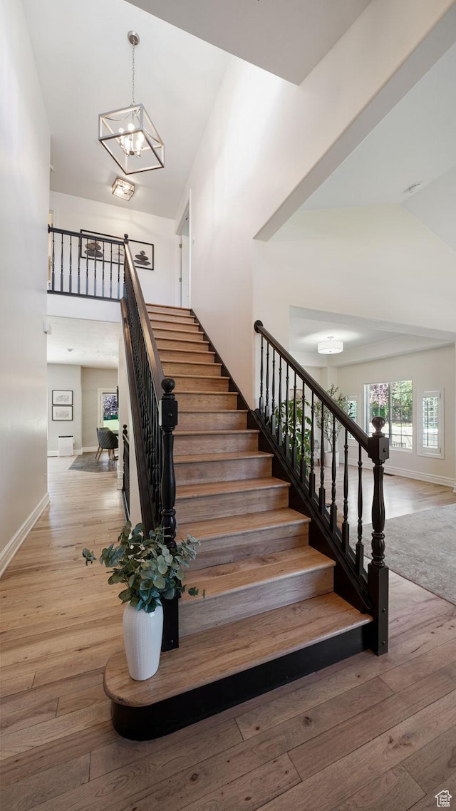 11597 N Sunset Hills Dr, Highland, UT 84003 - stairway with hardwood / wood-style flooring, a chandelier, and high vaulted ceiling