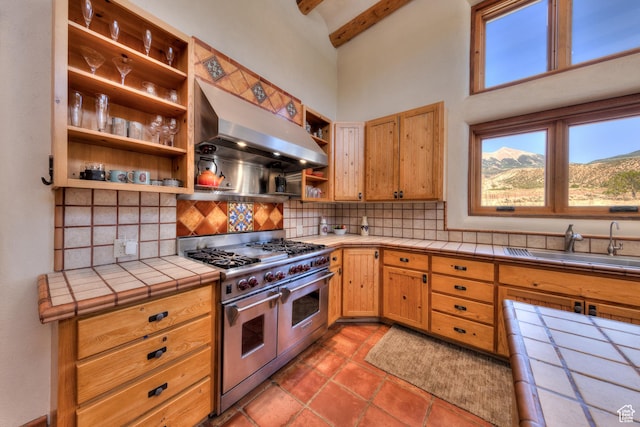 70 Desert Solitaire Rd, Moab, UT 84532 - kitchen featuring range with two ovens, open shelves, extractor fan, tile counters, and decorative backsplash