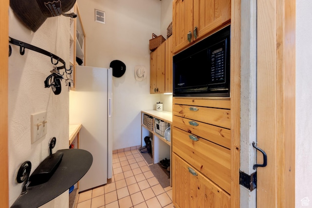 70 Desert Solitaire Rd, Moab, UT 84532 - kitchen with black microwave, light tile patterned floors, freestanding refrigerator, and light countertops