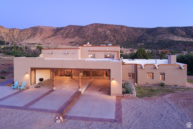 70 Desert Solitaire Rd, Moab, UT 84532 - pueblo-style house with concrete driveway, stucco siding, a mountain view, and a chimney