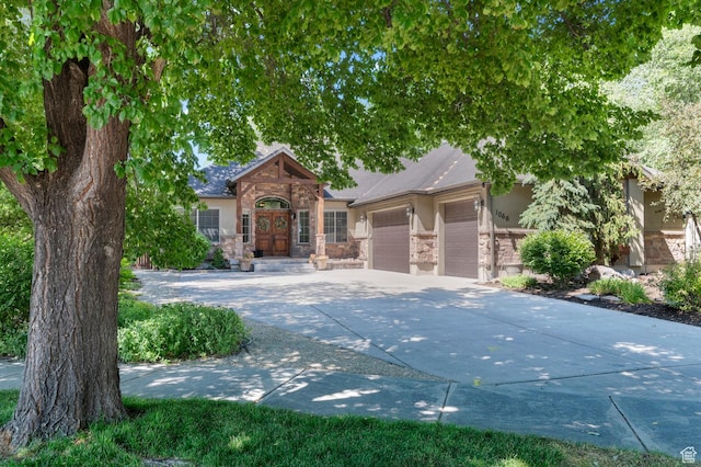 1066 W 575 N, Springville, UT 84663 - view of property hidden behind natural elements featuring stone siding, an attached garage, concrete driveway, and stucco siding