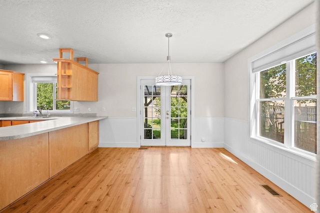 7861 N Tinamous Rd, Eagle Mountain, UT 84005 - kitchen with light wood-style flooring, open shelves, a wainscoted wall, a textured ceiling, and light countertops