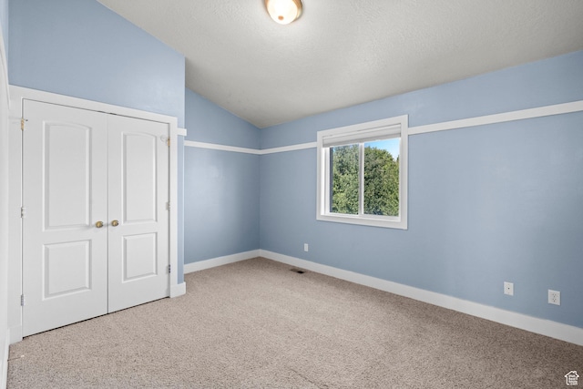 7861 N Tinamous Rd, Eagle Mountain, UT 84005 - unfurnished bedroom with vaulted ceiling, carpet floors, a closet, and a textured ceiling
