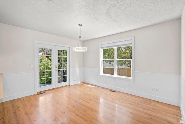 7861 N Tinamous Rd, Eagle Mountain, UT 84005 - empty room with a wainscoted wall, wood finished floors, a textured ceiling, and french doors