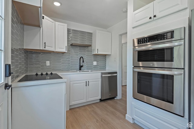943 W Signora Dr, Salt Lake City, UT 84116 - kitchen featuring appliances with stainless steel finishes, light wood-style flooring, white cabinets, backsplash, and light countertops