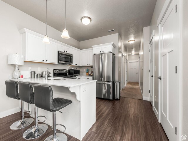523 N 310 W, Vineyard, UT 84059 - kitchen featuring stainless steel appliances, a peninsula, dark wood-type flooring, light countertops, and a breakfast bar