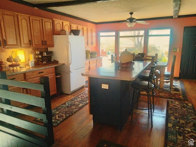 429 Edgehill Dr, Sunnyside, UT 84539 - kitchen with freestanding refrigerator, hardwood / wood-style flooring, a ceiling fan, a kitchen bar, and a center island