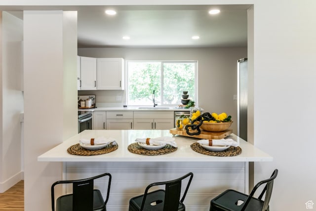 839 E Statice Ave S, Sandy, UT 84094 - kitchen with a kitchen bar, white cabinetry, light countertops, recessed lighting, and range