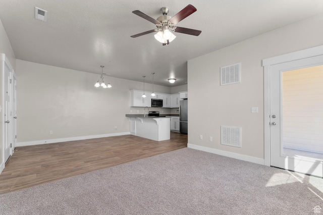 14643 S Mckellen Dr Unit D202, Herriman, UT 84096 - unfurnished living room featuring a chandelier, ceiling fan, carpet flooring, and wood finished floors