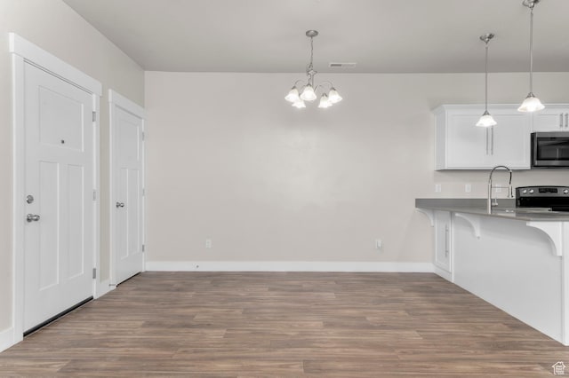 14643 S Mckellen Dr Unit D202, Herriman, UT 84096 - kitchen featuring appliances with stainless steel finishes, a chandelier, a kitchen bar, and wood finished floors
