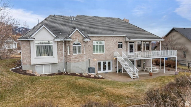 27 Canterbury Ln, Logan, UT 84321 - rear view of property featuring brick siding, a deck, a patio area, french doors, and a lawn