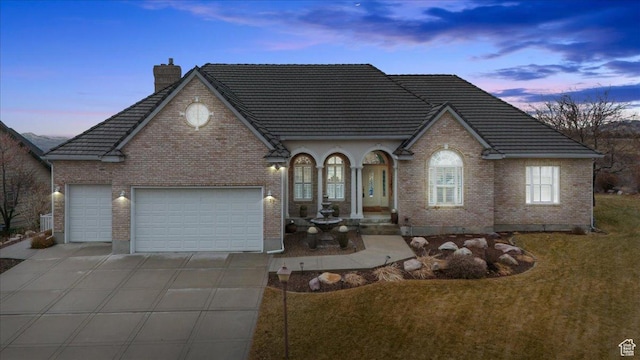 27 Canterbury Ln, Logan, UT 84321 - view of front of property with concrete driveway, a chimney, an attached garage, and brick siding