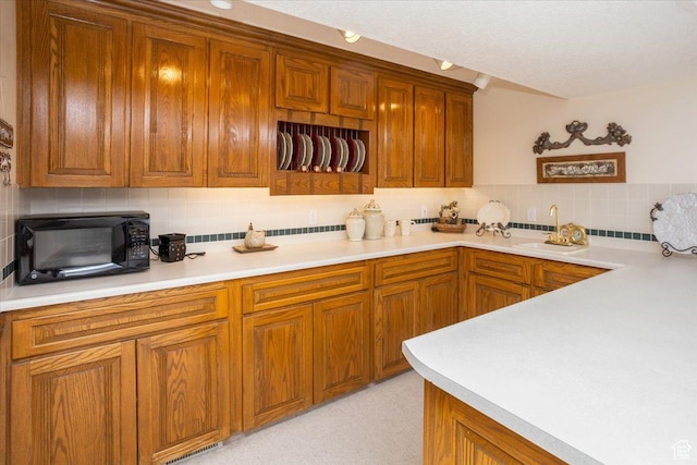 27 Canterbury Ln, Logan, UT 84321 - kitchen featuring black microwave, backsplash, brown cabinetry, and light countertops