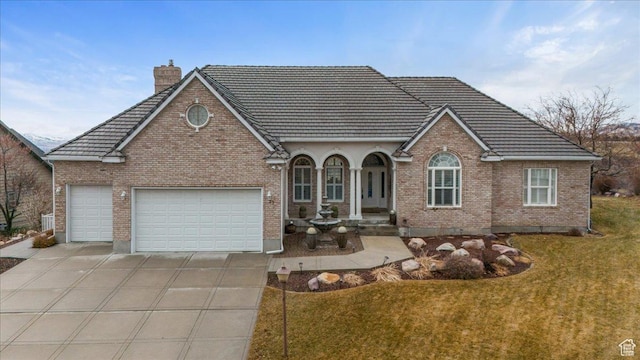 27 Canterbury Ln, Logan, UT 84321 - view of front of property featuring driveway, a front yard, a garage, brick siding, and a chimney