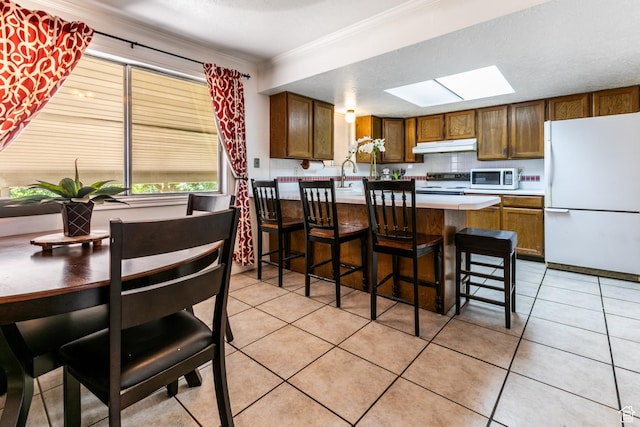 1844 Sorrento Dr, Woods Cross, UT 84087 - kitchen featuring freestanding refrigerator, electric range oven, a skylight, under cabinet range hood, and light tile patterned floors