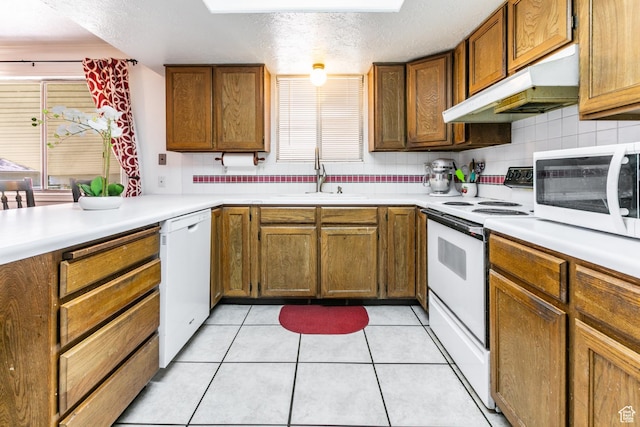 1844 Sorrento Dr, Woods Cross, UT 84087 - kitchen featuring white appliances, under cabinet range hood, light countertops, brown cabinetry, and a textured ceiling