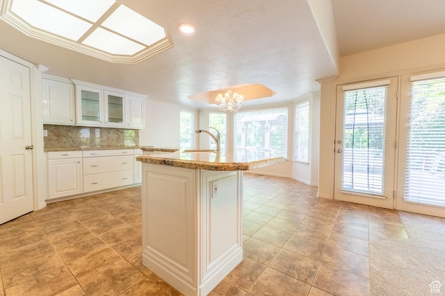 571 E Golden Pheasant Dr, Draper, UT 84020 - kitchen with a chandelier, light tile patterned floors, decorative backsplash, white cabinetry, and glass insert cabinets