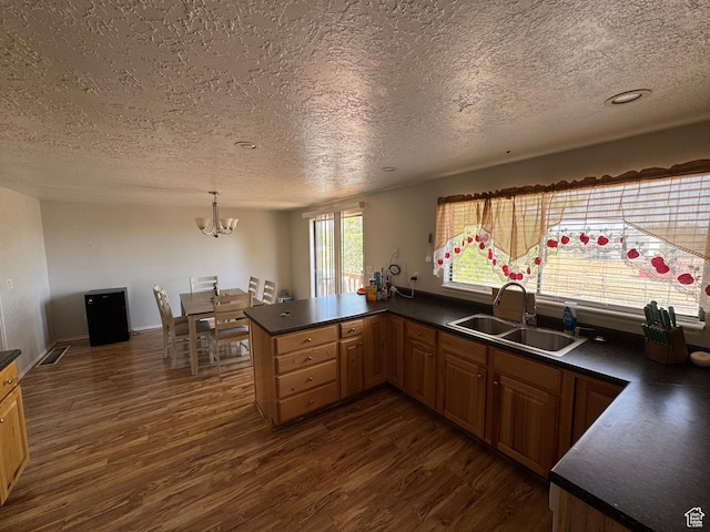 631 W Main St W, Wellington, UT 84542 - kitchen with a textured ceiling, dark wood-style floors, dark countertops, a chandelier, and a peninsula