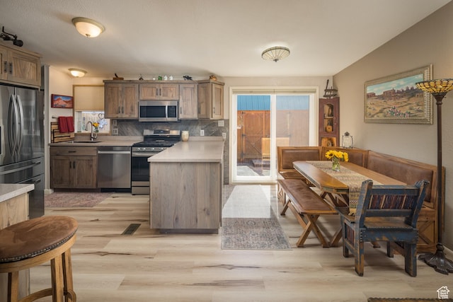 460 E Bowen Cir, Moab, UT 84532 - kitchen featuring appliances with stainless steel finishes, a peninsula, light wood-type flooring, tasteful backsplash, and light countertops