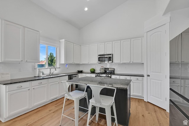874 W Steeple Chase Dr, Kaysville, UT 84037 - kitchen with stainless steel appliances, high vaulted ceiling, white cabinetry, dark stone countertops, and tasteful backsplash