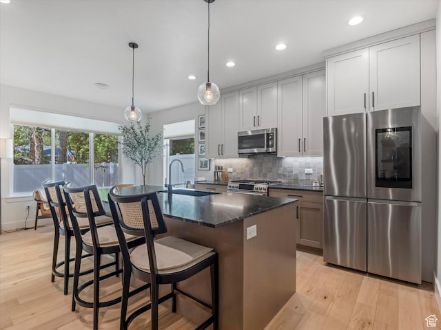 1783 E Bermondsey Ct, Holladay, UT 84117 - kitchen with appliances with stainless steel finishes, light wood-style flooring, tasteful backsplash, an island with sink, and recessed lighting