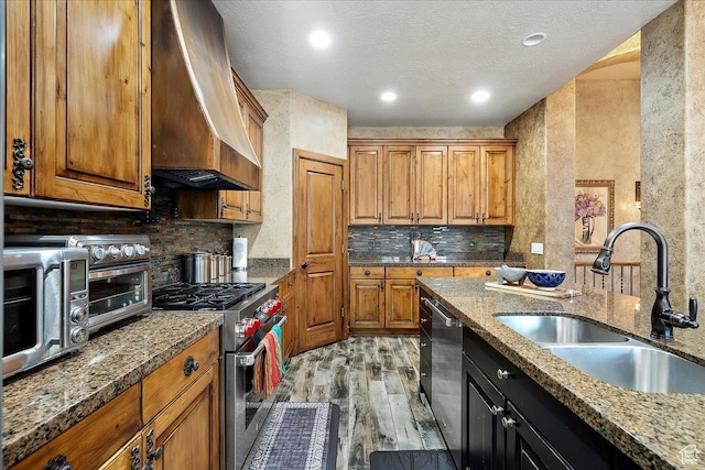3695 S 3525 W, West Haven, UT 84401 - kitchen with appliances with stainless steel finishes, wall chimney range hood, light wood-style floors, brown cabinets, and decorative backsplash