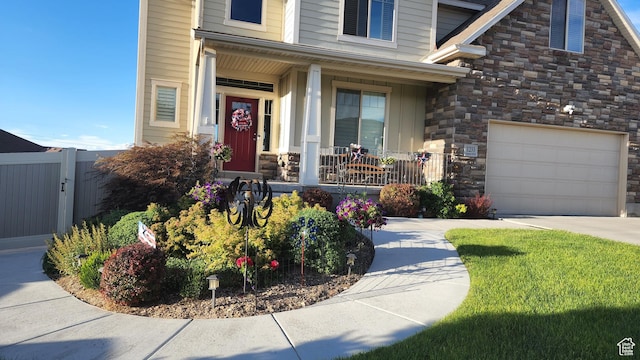 1233 E Upland Dr S Unit 112, Tooele, UT 84074 - doorway to property with a porch, stone siding, a garage, and concrete driveway