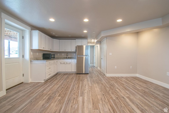 1233 E Upland Dr S Unit 112, Tooele, UT 84074 - kitchen featuring freestanding refrigerator, light wood-style flooring, recessed lighting, white cabinetry, and light stone counters
