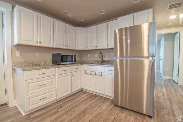 1233 E Upland Dr S Unit 112, Tooele, UT 84074 - kitchen with appliances with stainless steel finishes, light wood-type flooring, white cabinets, and light stone countertops
