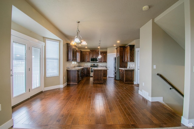 1233 E Upland Dr S Unit 112, Tooele, UT 84074 - kitchen with stainless steel appliances, a kitchen island, dark brown cabinets, dark wood-type flooring, and pendant lighting