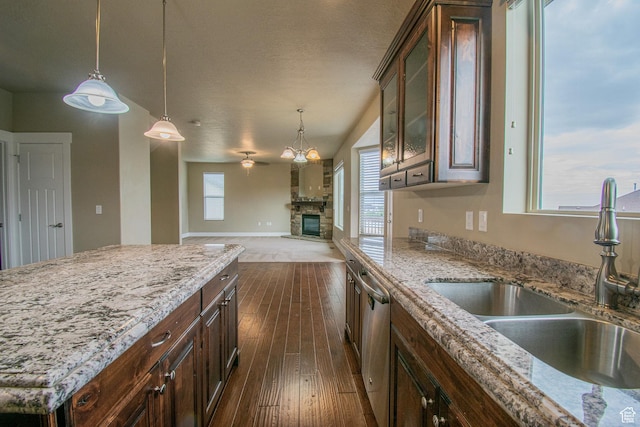 1233 E Upland Dr S Unit 112, Tooele, UT 84074 - kitchen featuring dishwasher, dark wood-style floors, a stone fireplace, hanging light fixtures, and light stone countertops