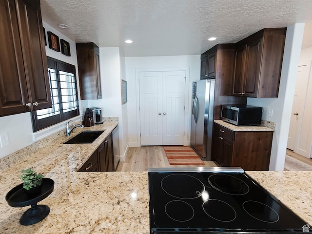 926 N 165 W, Nephi, UT 84648 - kitchen with stainless steel appliances, dark brown cabinetry, light wood-style flooring, light stone countertops, and a textured ceiling
