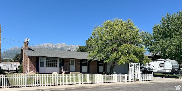 663 E 485 S, Orem, UT 84097 - ranch-style home featuring brick siding, a chimney, a shingled roof, a fenced front yard, and a mountain view