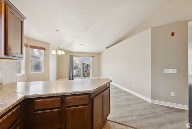 8229 S Resaca Dr Unit D11, Sandy, UT 84070 - kitchen with a peninsula, a chandelier, plenty of natural light, light wood-style flooring, and lofted ceiling