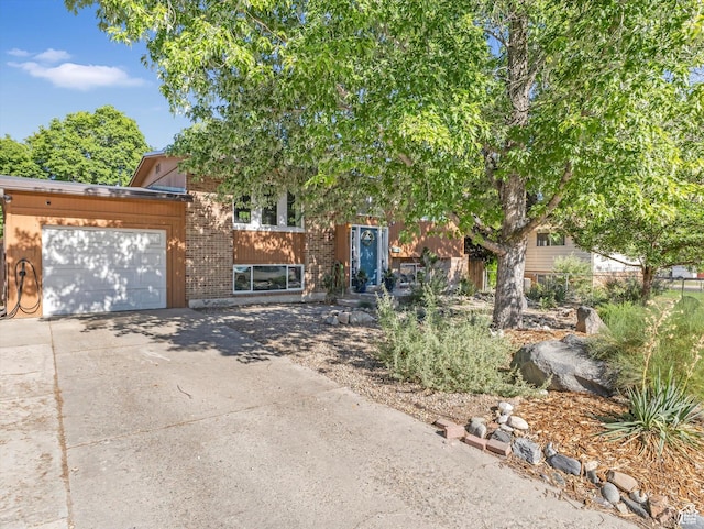 9457 S Poppy Ln, Sandy, UT 84094 - view of property hidden behind natural elements featuring a garage, concrete driveway, and brick siding