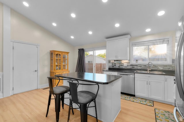 3558 S Chippewa Rd, West Valley City, UT 84120 - kitchen with appliances with stainless steel finishes, dark countertops, a center island, a breakfast bar, and vaulted ceiling