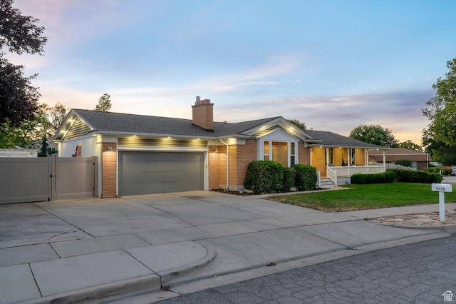 3558 S Chippewa Rd, West Valley City, UT 84120 - ranch-style house featuring brick siding, a gate, concrete driveway, a lawn, and covered porch