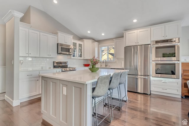10768 N Fiddlesticks Lot 30, Cedar Hills, UT 84062 - kitchen featuring appliances with stainless steel finishes, white cabinets, light wood-style flooring, a kitchen island, and vaulted ceiling