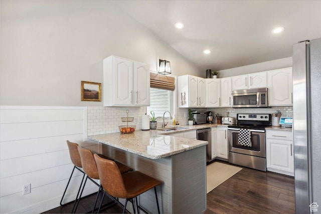 1184 Bridgecreek Ln, Layton, UT 84041 - kitchen with appliances with stainless steel finishes, a peninsula, vaulted ceiling, white cabinets, and decorative backsplash