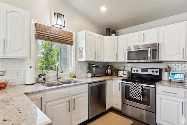 1184 Bridgecreek Ln, Layton, UT 84041 - kitchen featuring appliances with stainless steel finishes, white cabinetry, vaulted ceiling, backsplash, and light stone countertops
