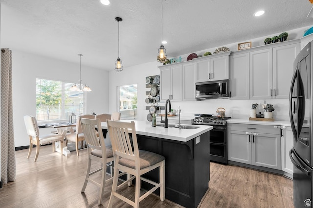 5631 W Still Well Ln S, Herriman, UT 84096 - kitchen with stainless steel appliances, light countertops, light wood finished floors, a kitchen breakfast bar, and recessed lighting