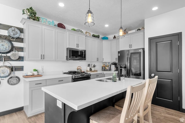 5631 W Still Well Ln S, Herriman, UT 84096 - kitchen featuring stainless steel appliances, light countertops, a breakfast bar area, light wood-style flooring, and recessed lighting