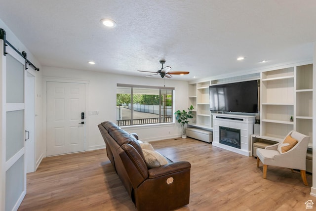 249 N 800 W, Orem, UT 84057 - living room with a barn door, light wood-style floors, a ceiling fan, a fireplace, and recessed lighting