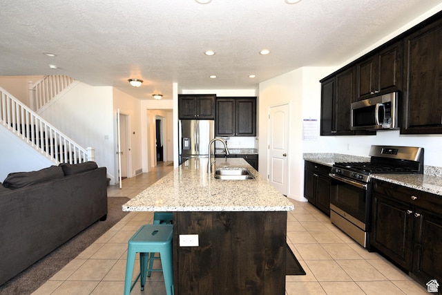 4666 W Olympic Wood Ct, West Jordan, UT 84084 - kitchen with appliances with stainless steel finishes, light tile patterned flooring, a kitchen bar, open floor plan, and light stone countertops