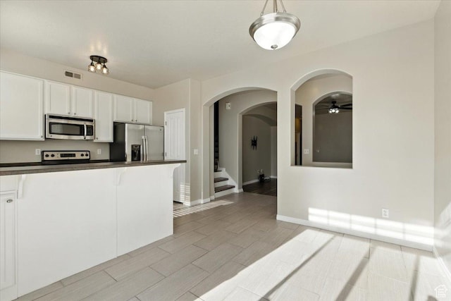 729 N Buckingham Dr W, North Salt Lake, UT 84054 - kitchen with stainless steel appliances, dark countertops, arched walkways, a ceiling fan, and white cabinets
